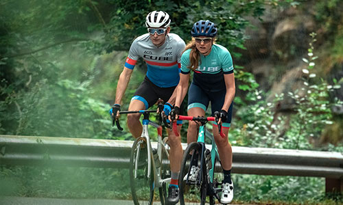 Mies ja nainen ajavat cyclocross-kilpapyörillä tiellä.